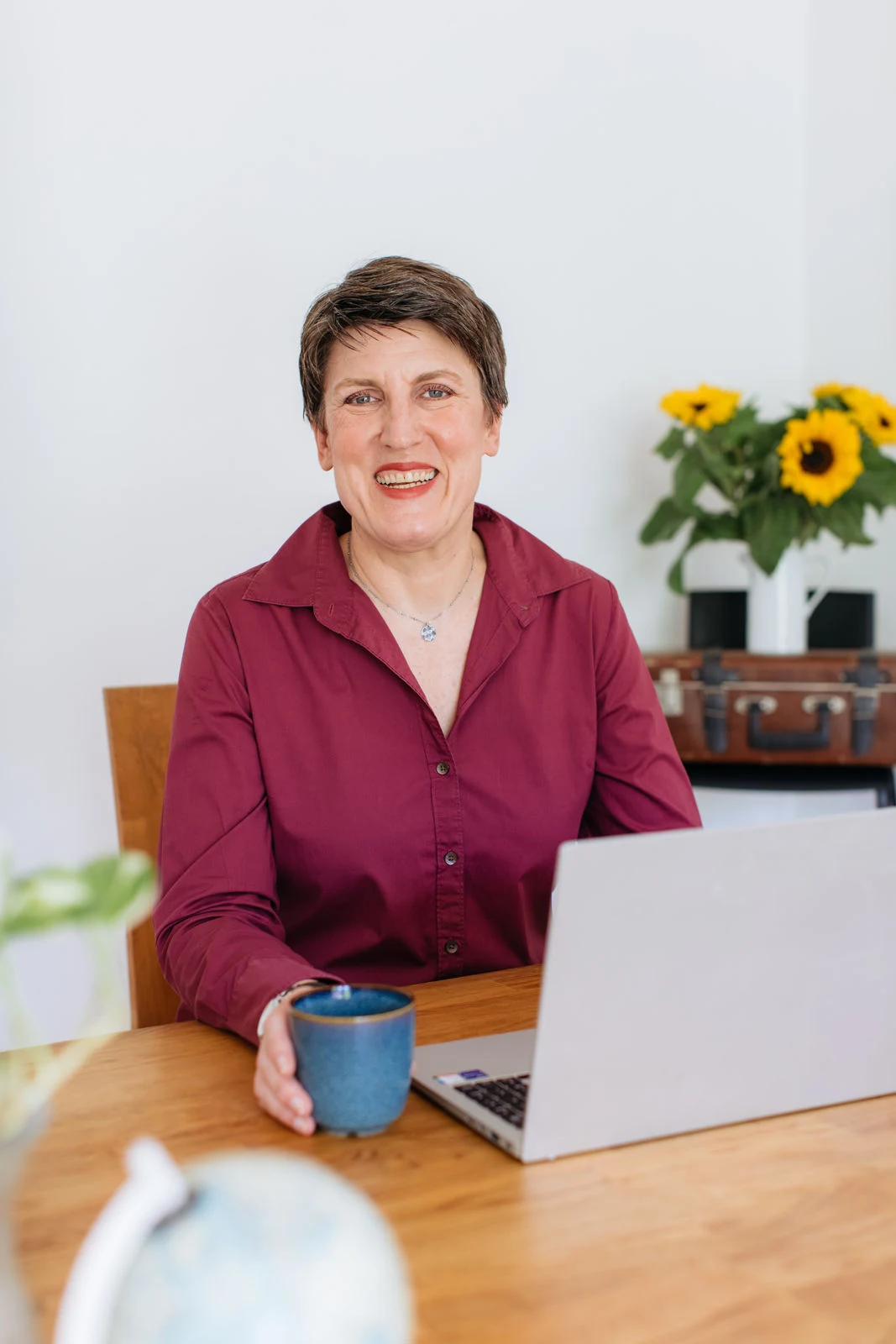 Angela Harde von Senior Aupair am Tisch mit Laptop und Tasse.